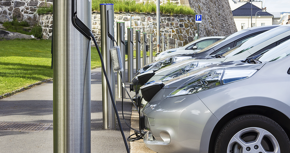 Row of electric cars at charging ports.